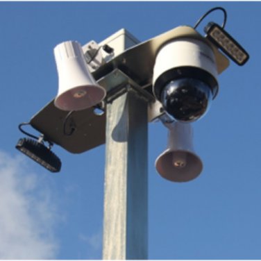 Outdoor CCTV camera with flood lights and loud speakers against a backdrop of blue sky and white clouds