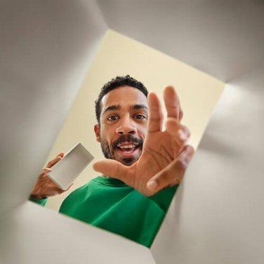 Man holding a phone, reaching into a box