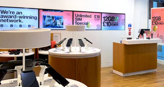Inside of a Three store with advertising screens and mobile phones on display