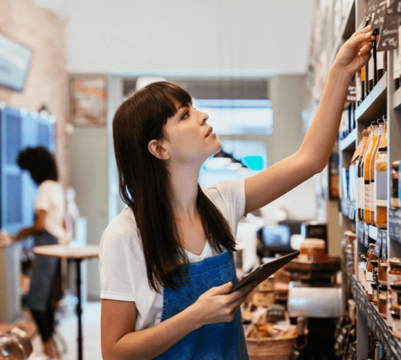 Woman working in a shop checking goods on shelf
